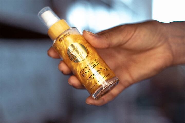 Golden Glow Body Oil Glasflasche in einer Hand